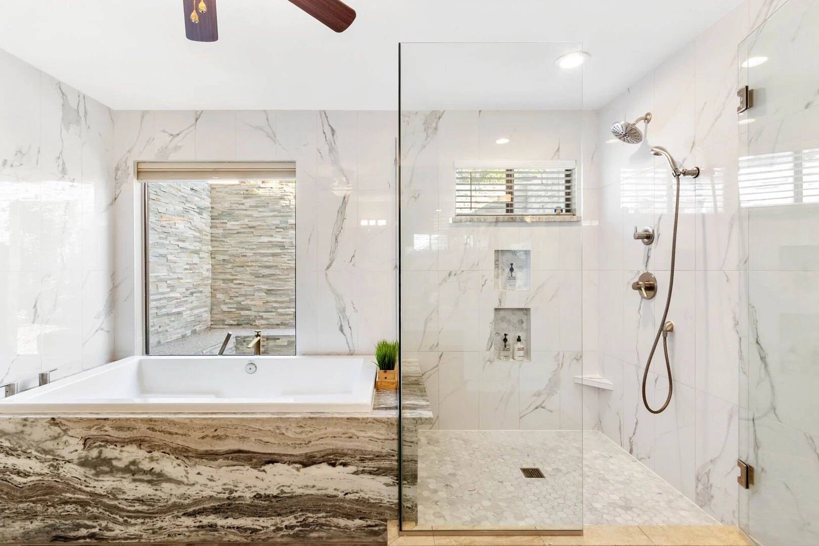 Primary bath with marble tile, soaking tub and curbless glass shower