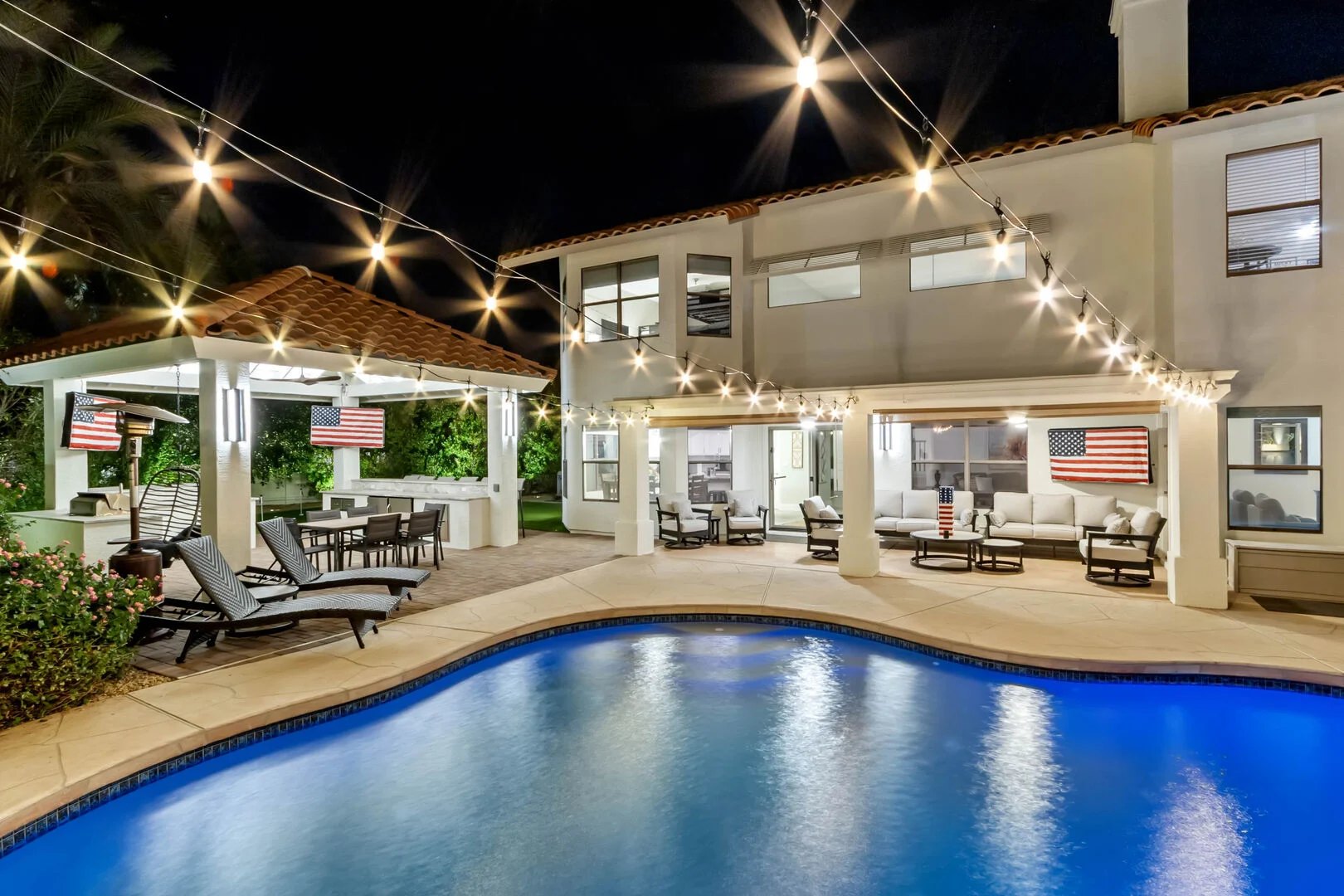 Remodeled rear elevation and pool lit by string lights at night