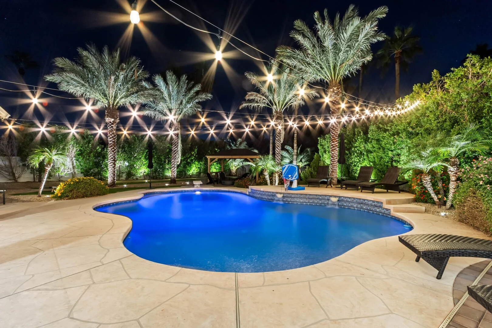 Backyard remodel with a lit pool and string lights in Phoenix