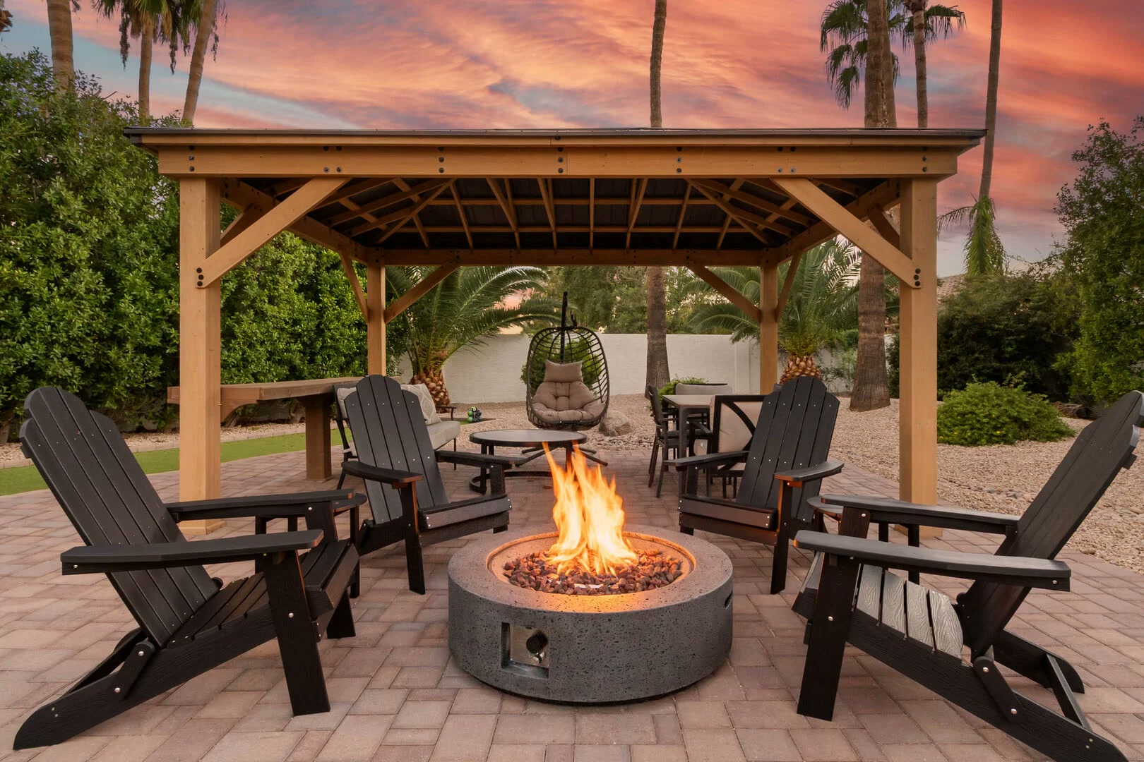 Outdoor living project with a gazebo and stone fire pit at dusk